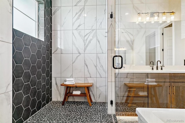 bathroom with vanity, a shower with shower door, and tile walls