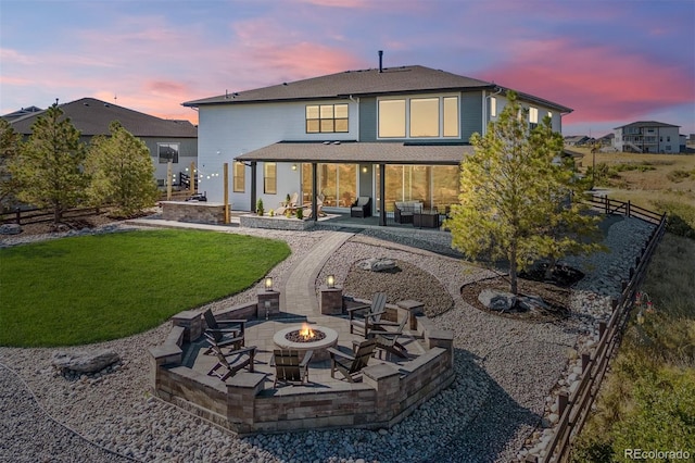 back house at dusk with a patio, a yard, and a fire pit