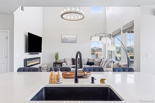 kitchen with a glass covered fireplace, open floor plan, light countertops, and a sink