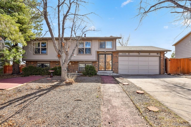 view of front facade with fence, driveway, stucco siding, a garage, and brick siding