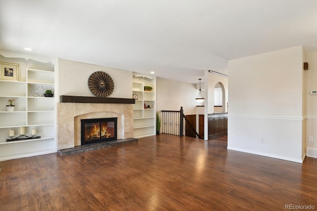 unfurnished living room featuring visible vents, baseboards, a tiled fireplace, built in features, and wood finished floors