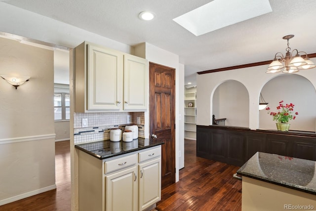 kitchen featuring backsplash, pendant lighting, dark stone counters, a notable chandelier, and dark wood-style flooring