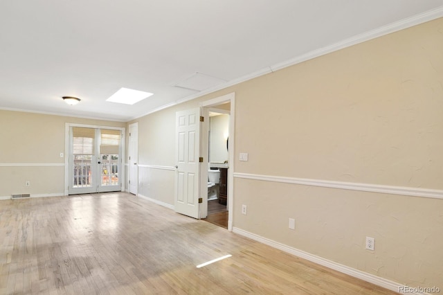 empty room with visible vents, baseboards, wood finished floors, and crown molding