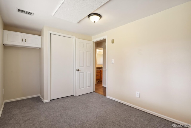 unfurnished bedroom featuring visible vents, baseboards, a closet, and carpet flooring