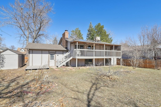 back of property with fence, a shed, stucco siding, a chimney, and an outbuilding