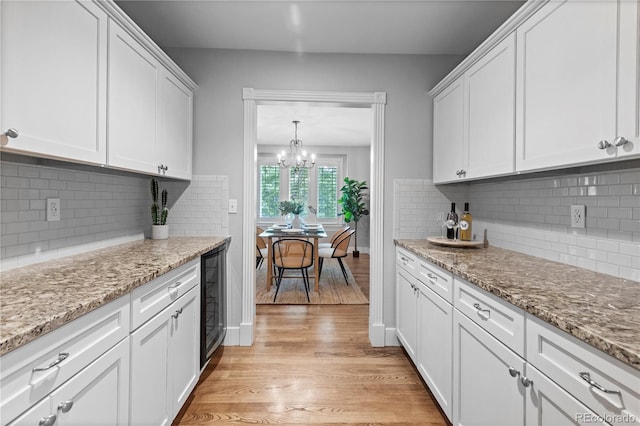 1366 S Vine St, Denver, CO 80210 - kitchen with white cabinets, light wood finished floors, tasteful backsplash, a chandelier, and wine cooler
