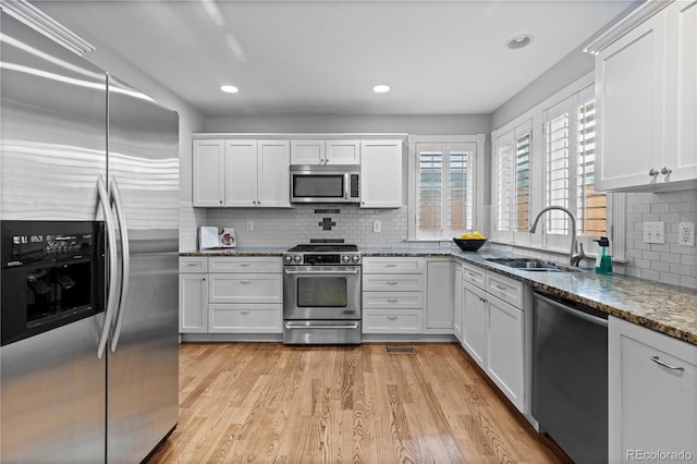 1366 S Vine St, Denver, CO 80210 - kitchen with stainless steel appliances, a sink, white cabinetry, decorative backsplash, and light wood-style floors
