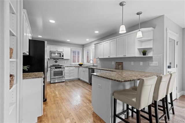 1366 S Vine St, Denver, CO 80210 - kitchen featuring appliances with stainless steel finishes, a peninsula, a sink, open shelves, and light wood-type flooring