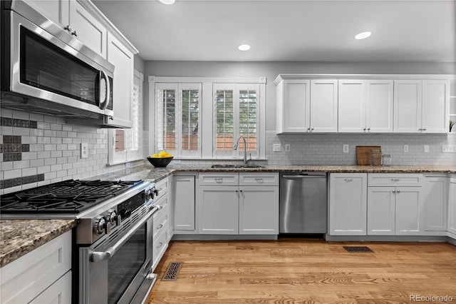 1366 S Vine St, Denver, CO 80210 - kitchen featuring stainless steel appliances, a sink, white cabinets, recessed lighting, and light wood-style flooring