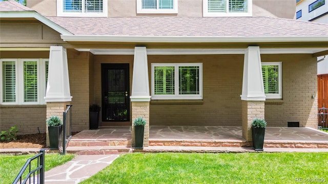 1366 S Vine St, Denver, CO 80210 - view of exterior entry featuring brick siding, roof with shingles, and a porch