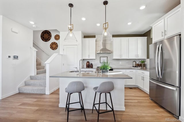 kitchen with white cabinetry, an island with sink, stainless steel fridge, and sink