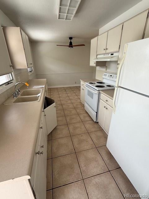 kitchen featuring white appliances, light tile patterned floors, sink, and white cabinets