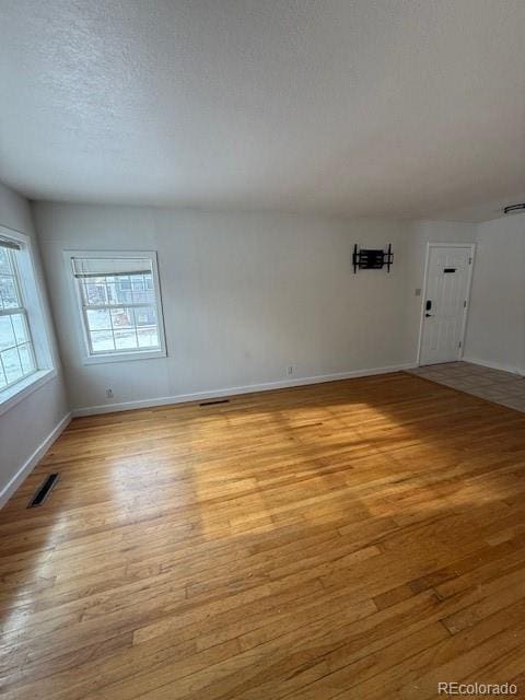 empty room with a textured ceiling and light wood-type flooring