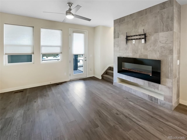 11267 Central Ct, Broomfield, CO 80021 - unfurnished living room featuring wood finished floors, a ceiling fan, a tiled fireplace, and stairs