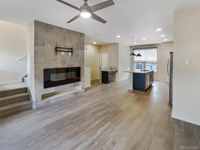 11267 Central Ct, Broomfield, CO 80021 - unfurnished living room featuring a tiled fireplace, ceiling fan, light wood-style flooring, stairs, and recessed lighting
