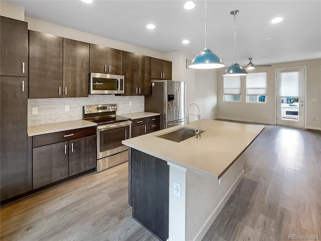 11267 Central Ct, Broomfield, CO 80021 - kitchen featuring appliances with stainless steel finishes, light countertops, dark brown cabinetry, light wood-style flooring, and recessed lighting