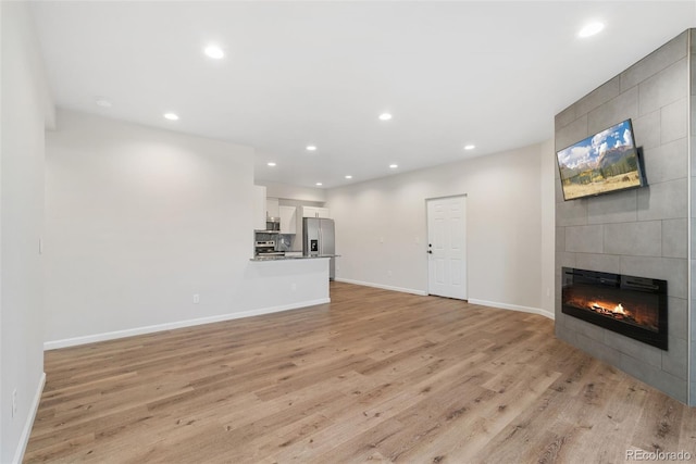 875 E 78th Ave Unit 52, Denver, CO 80229 - unfurnished living room with light wood-style floors, a tile fireplace, baseboards, and recessed lighting