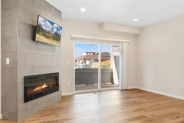 875 E 78th Ave Unit 52, Denver, CO 80229 - unfurnished living room with a tiled fireplace, wood finished floors, baseboards, and recessed lighting