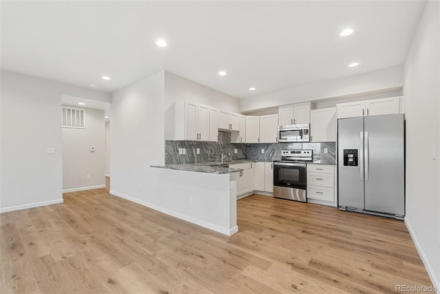 875 E 78th Ave Unit 52, Denver, CO 80229 - kitchen with stainless steel appliances, light wood-style floors, white cabinets, backsplash, and recessed lighting