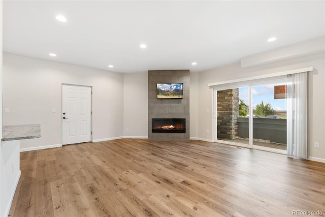 875 E 78th Ave Unit 52, Denver, CO 80229 - unfurnished living room with light wood-type flooring, recessed lighting, a tiled fireplace, and baseboards