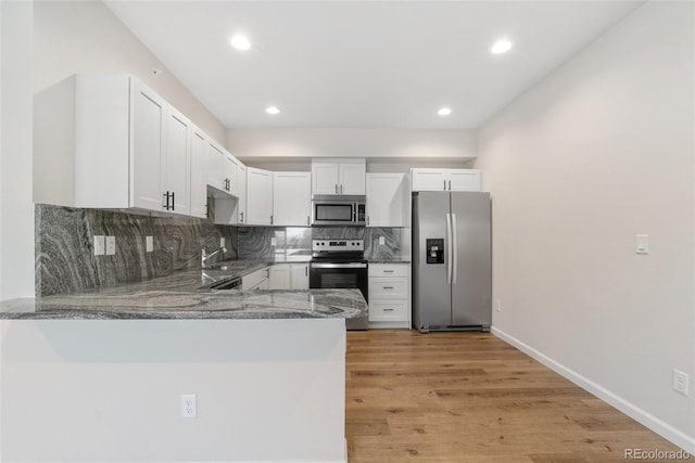 875 E 78th Ave Unit 52, Denver, CO 80229 - kitchen with stainless steel appliances, stone counters, a peninsula, tasteful backsplash, and white cabinetry
