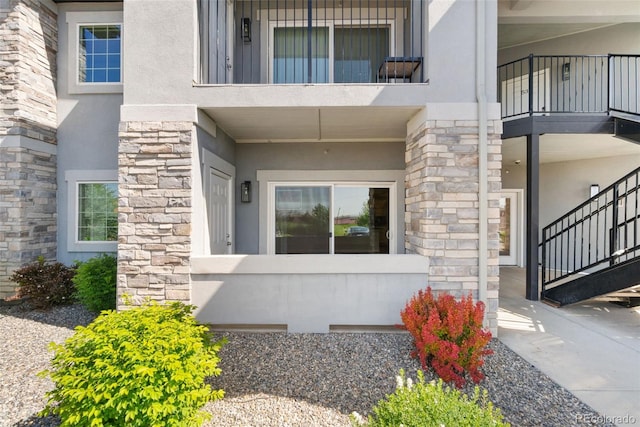 875 E 78th Ave Unit 52, Denver, CO 80229 - view of exterior entry with stucco siding, stone siding, and a balcony