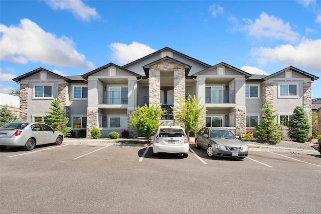 875 E 78th Ave Unit 52, Denver, CO 80229 - view of property featuring stone siding, stucco siding, and uncovered parking