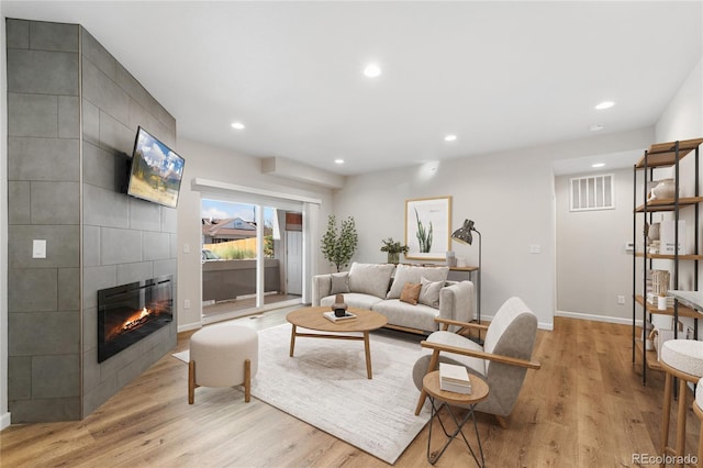 875 E 78th Ave Unit 52, Denver, CO 80229 - living room featuring baseboards, a tiled fireplace, light wood-type flooring, and recessed lighting