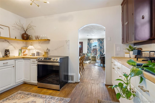 kitchen featuring white cabinetry, stainless steel electric stove, light hardwood / wood-style floors, and backsplash