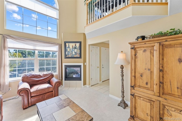 carpeted living room featuring a high ceiling and a fireplace