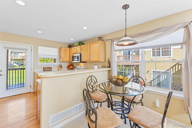 dining space with light hardwood / wood-style flooring and a healthy amount of sunlight