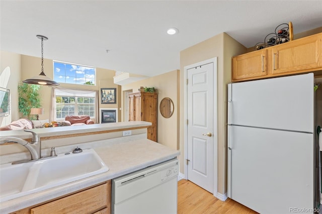 kitchen featuring light brown cabinets, sink, white appliances, decorative light fixtures, and light hardwood / wood-style flooring