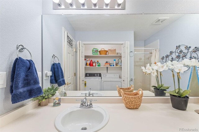 bathroom with vanity, washer and clothes dryer, and curtained shower