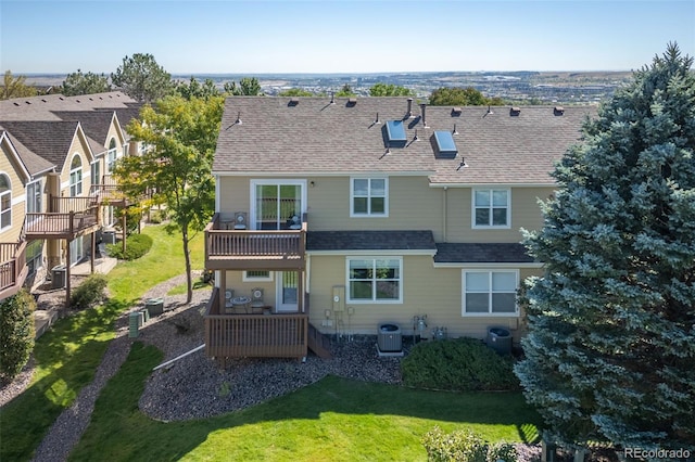 back of property featuring a wooden deck, cooling unit, a balcony, and a lawn