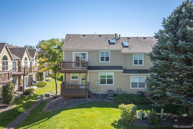 rear view of property with a balcony, a wooden deck, a yard, and central AC