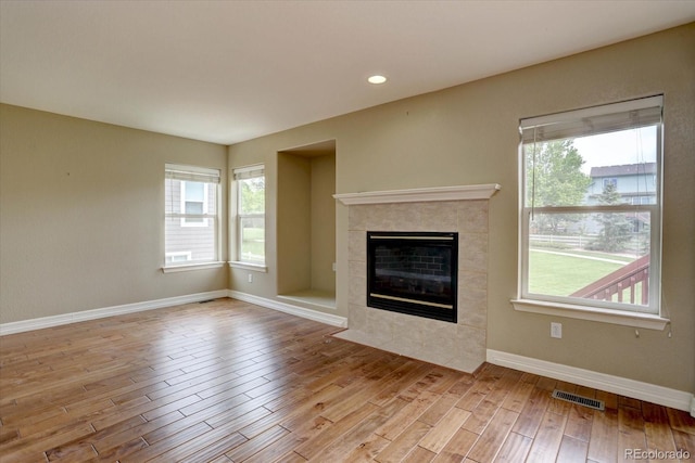 2253 E 100th Pl, Thornton, CO 80229 - unfurnished living room featuring plenty of natural light, wood finished floors, a tile fireplace, baseboards, and recessed lighting