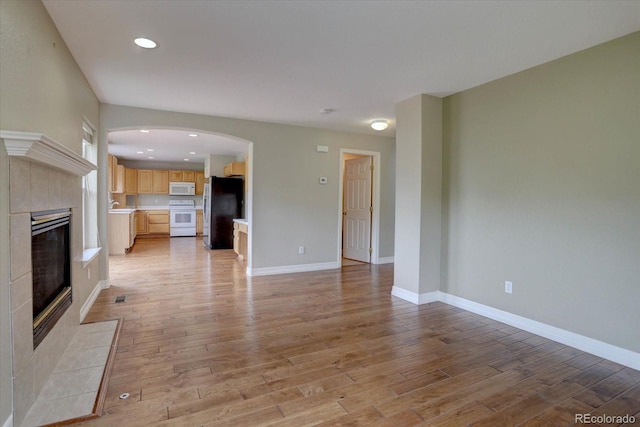 2253 E 100th Pl, Thornton, CO 80229 - unfurnished living room featuring a fireplace, arched walkways, light wood finished floors, baseboards, and recessed lighting
