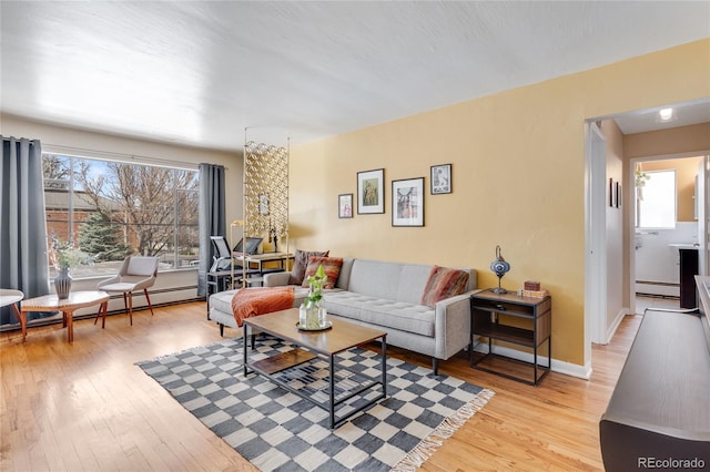 living room with light wood-style floors, baseboards, a baseboard heating unit, and baseboard heating