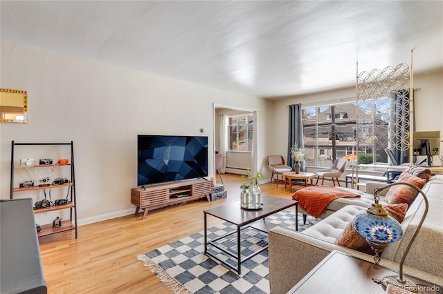 living area featuring baseboard heating, baseboards, and wood finished floors