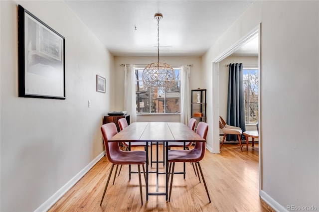 dining area with light wood-style floors, an inviting chandelier, and a wealth of natural light