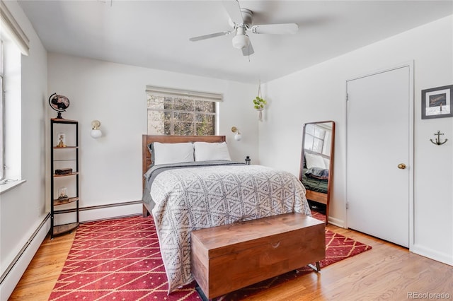 bedroom featuring light wood-type flooring, ceiling fan, and baseboard heating