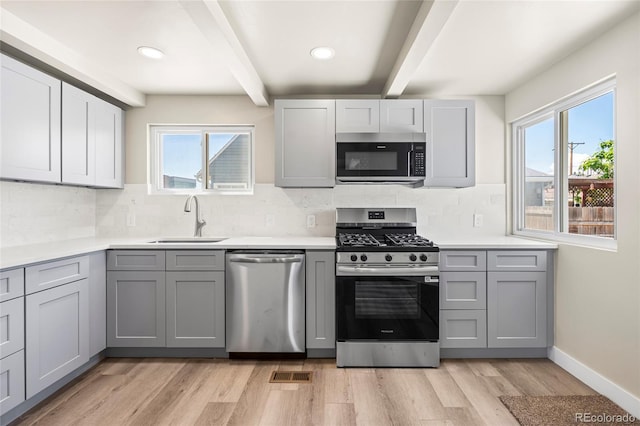 235 S 8th Ave, Brighton, CO 80601 - kitchen with stainless steel appliances, a sink, gray cabinetry, beamed ceiling, and light wood-type flooring