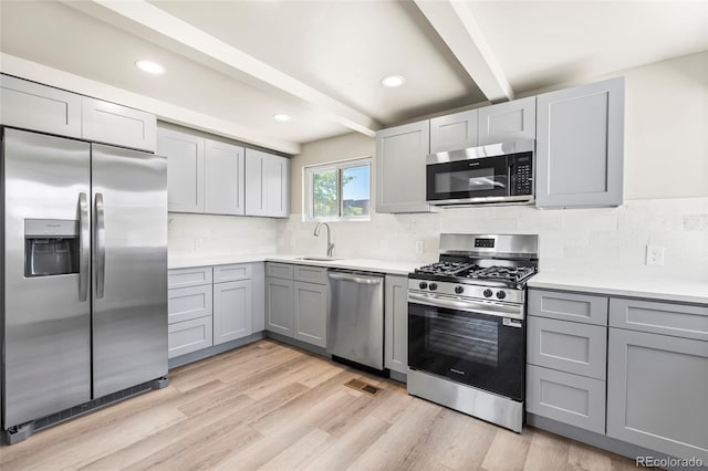 235 S 8th Ave, Brighton, CO 80601 - kitchen featuring stainless steel appliances, gray cabinetry, beam ceiling, a sink, and light wood-style floors