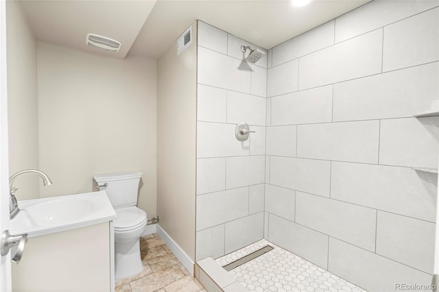 235 S 8th Ave, Brighton, CO 80601 - bathroom featuring vanity, toilet, a tile shower, and baseboards