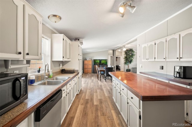 kitchen featuring white cabinetry, stainless steel appliances, lofted ceiling, and light wood-type flooring