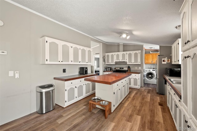 kitchen with wooden counters, electric range, hardwood / wood-style floors, a center island, and washer / dryer