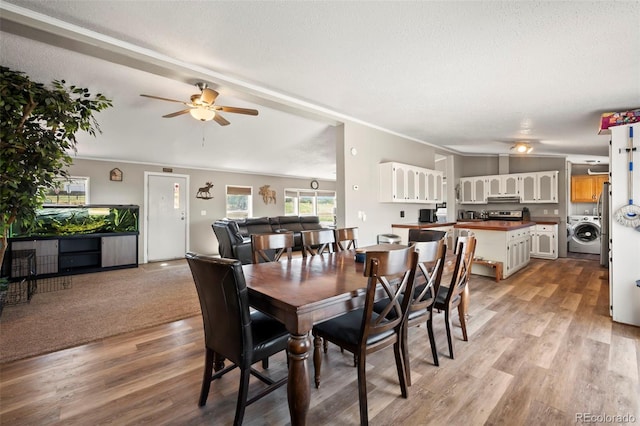 dining area with ceiling fan, light hardwood / wood-style flooring, a textured ceiling, and washer / dryer