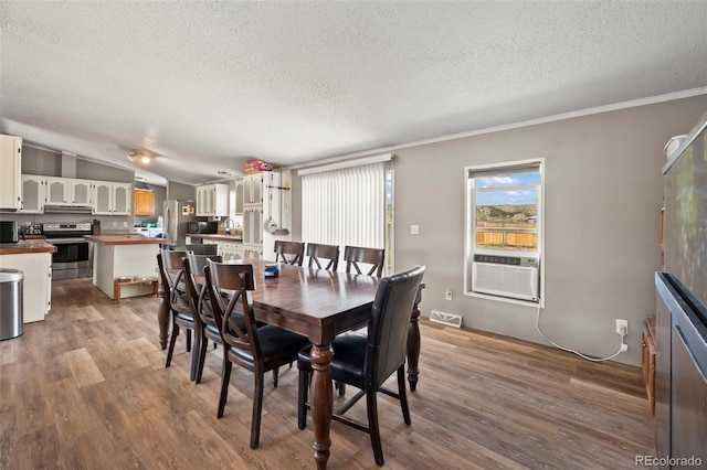 dining space with lofted ceiling, cooling unit, crown molding, hardwood / wood-style flooring, and a textured ceiling