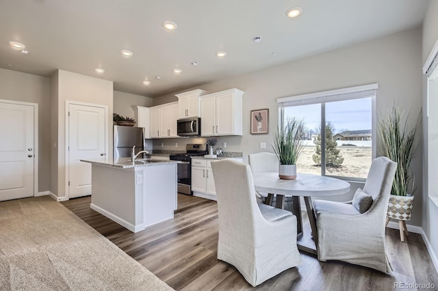 kitchen with recessed lighting, a center island with sink, appliances with stainless steel finishes, and white cabinets