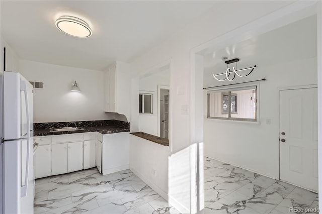 kitchen with white cabinetry, sink, and white fridge